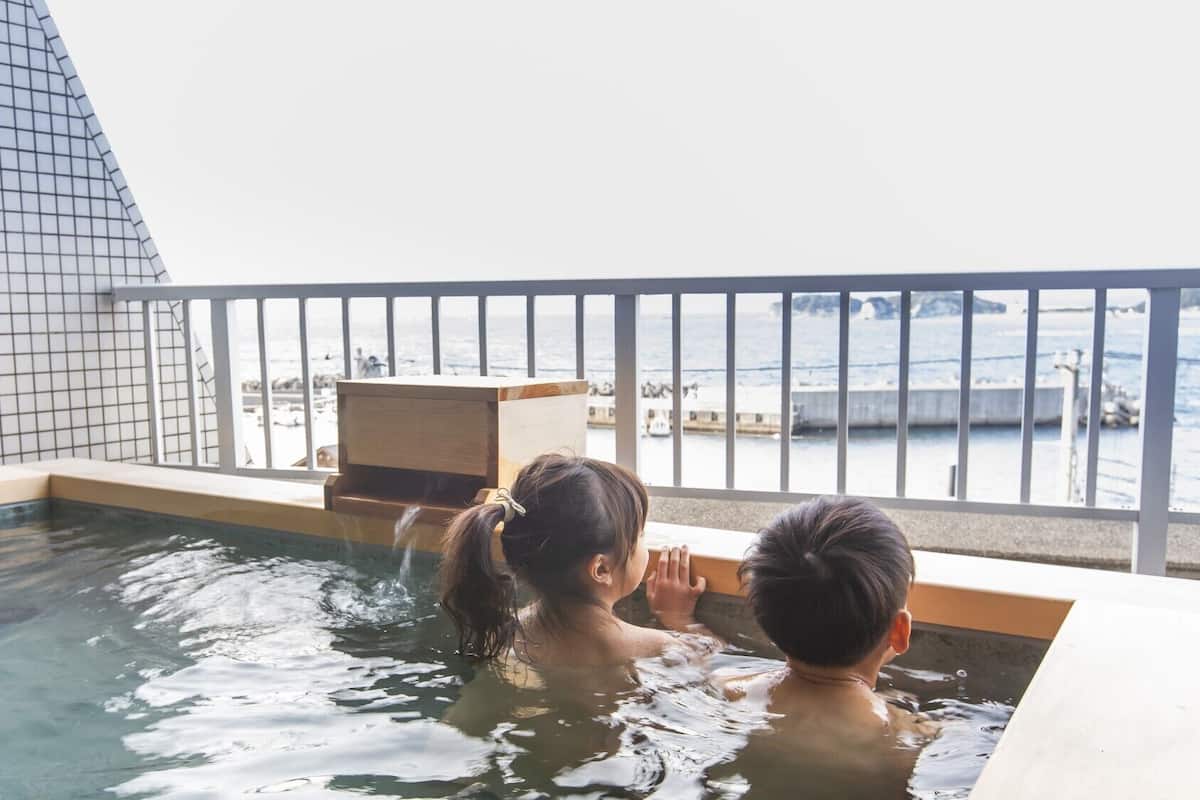 A hot tub with a view of the sea and a tiled wall.