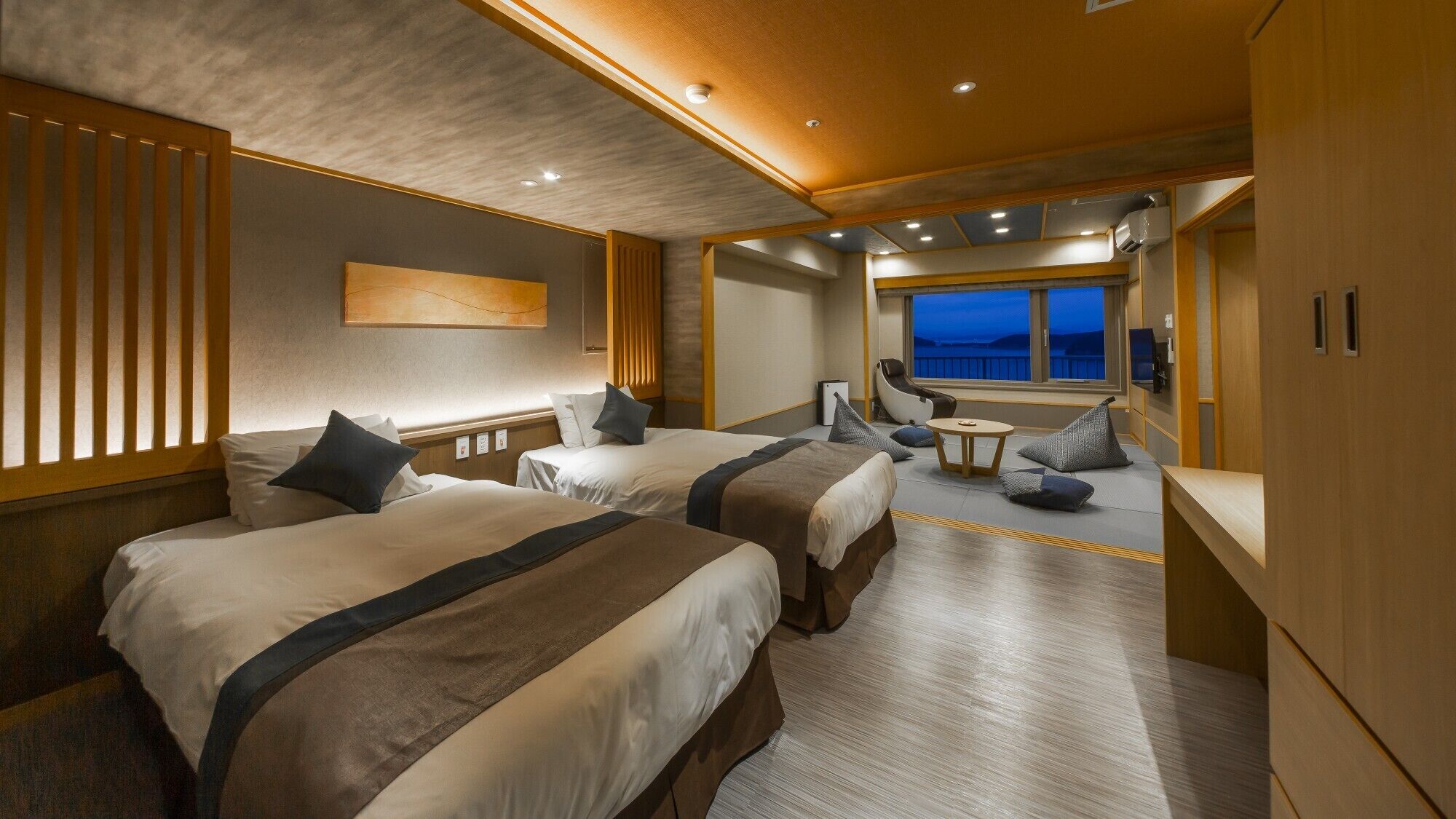 A hotel room with two beds, a seating area, and a large window with a view.
