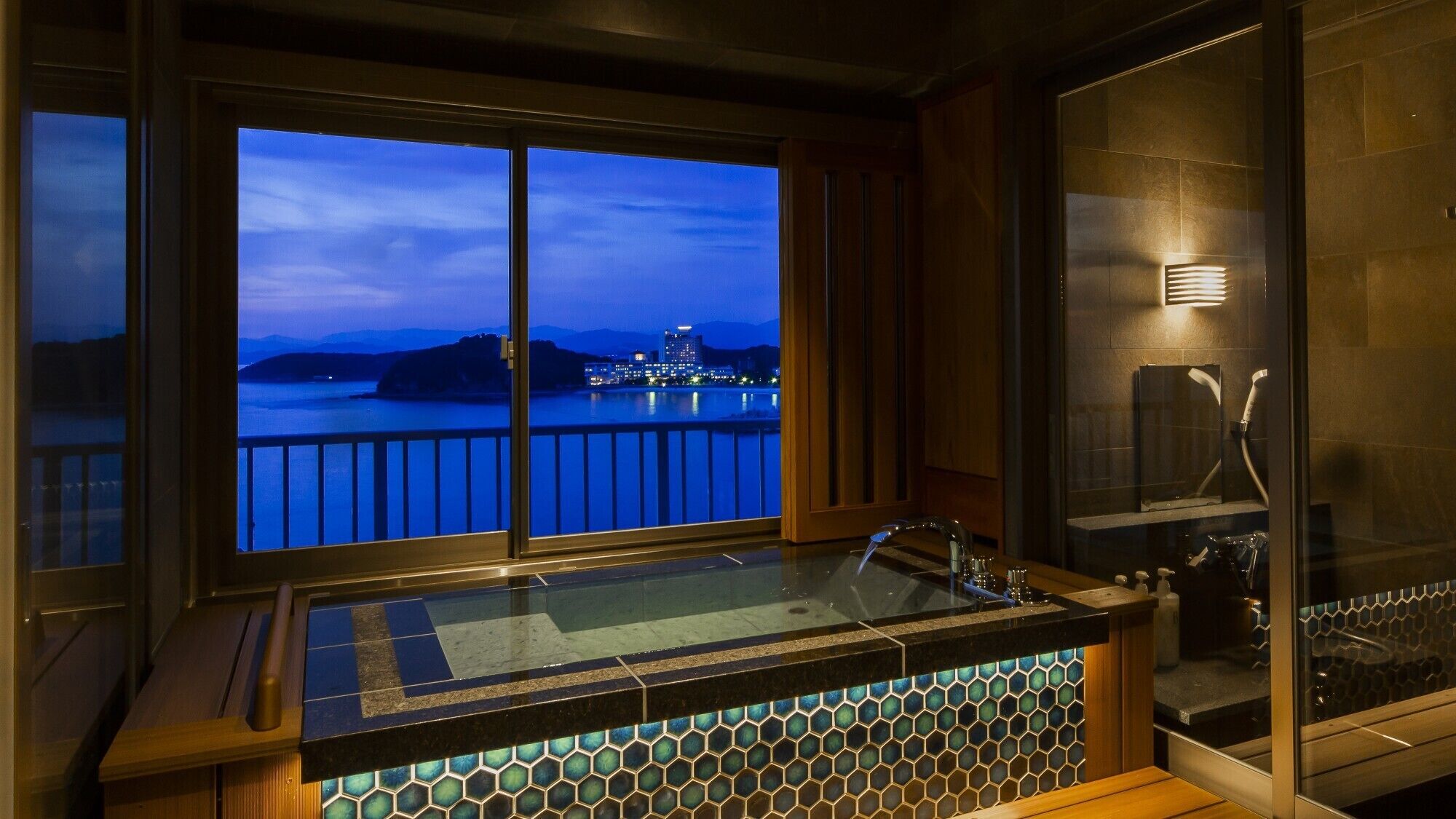 A bathtub with a view of a cityscape at dusk.