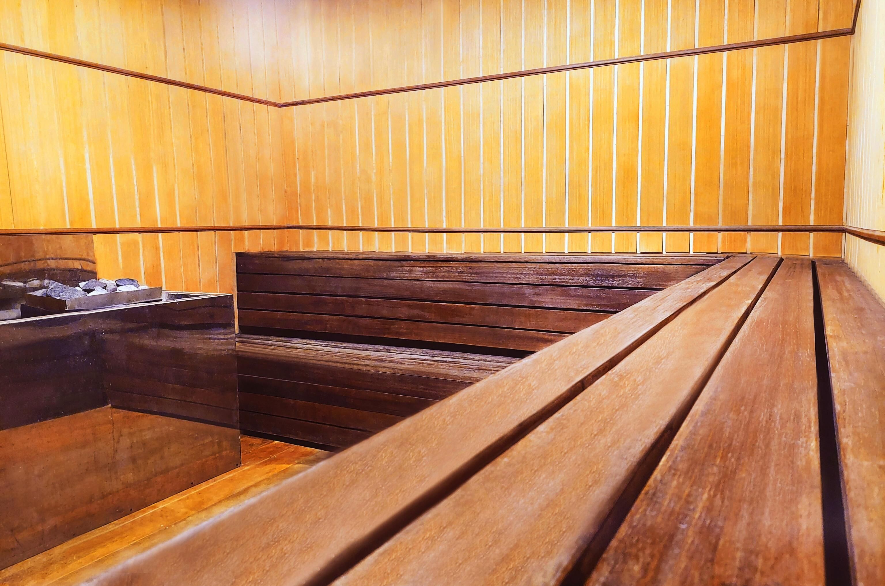 A wooden sauna with benches and a stone basin.