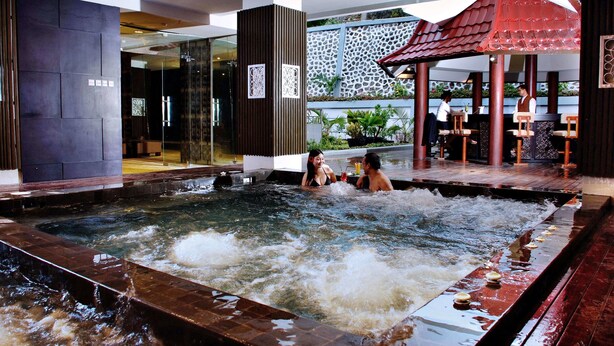 A spa area with a hot tub, wooden seating, and a decorative wall. - Aston Jayapura Hotel & Convention Center (Jayapura)