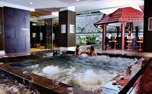 A spa area with a hot tub, wooden seating, and a decorative wall.