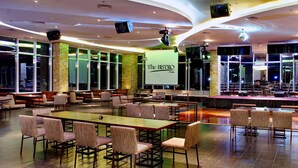 A spacious indoor area with tables and chairs, a stage with musical instruments, and a sign reading "The BISTRO Pub". - Aston Jayapura Hotel & Convention Center (Jayapura)