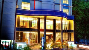 A modern hotel with a curved facade, large windows, and a central entrance with a staircase. - Aston Jayapura Hotel & Convention Center (Jayapura)