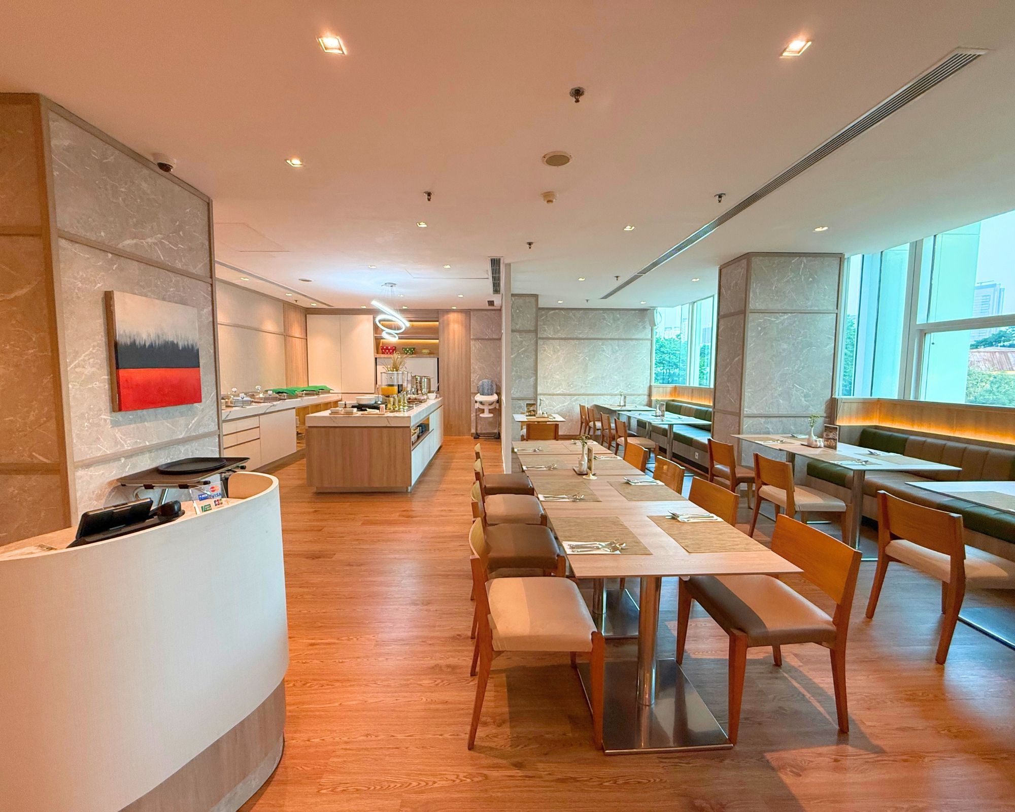 Un restaurante moderno con una larga mesa de comedor, sillas de madera y una zona de cocina al fondo.