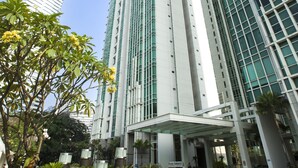 A modern hotel with tall buildings, a covered entrance, and a landscaped garden area.