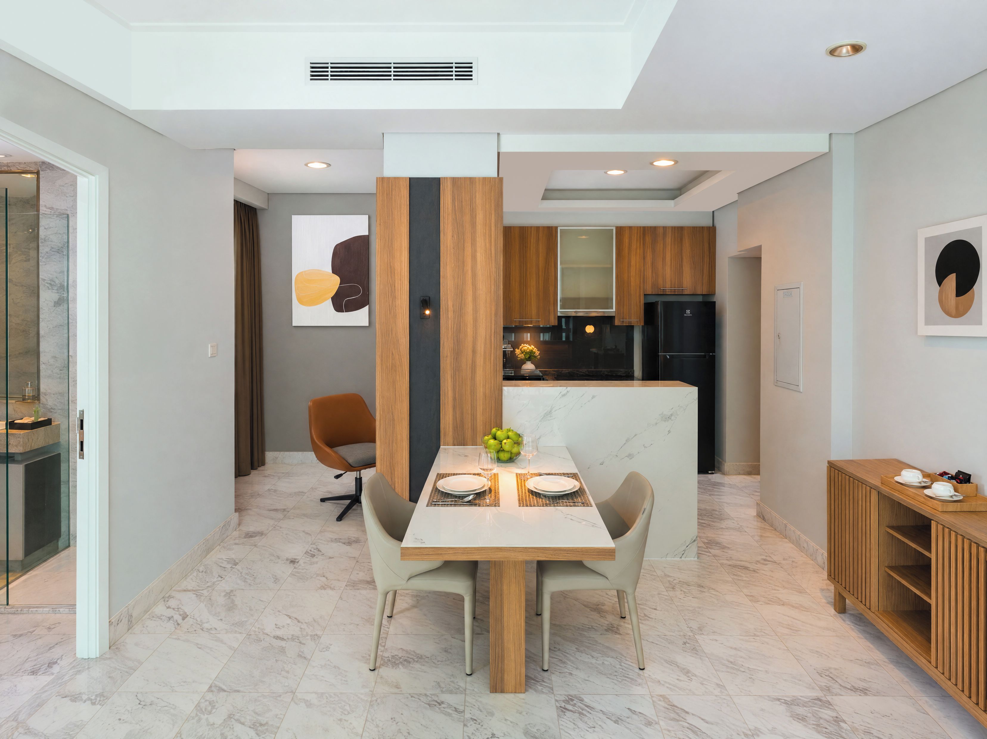 Una cocina moderna con una isla central, un comedor con mesa de mármol y un refrigerador empotrado.
