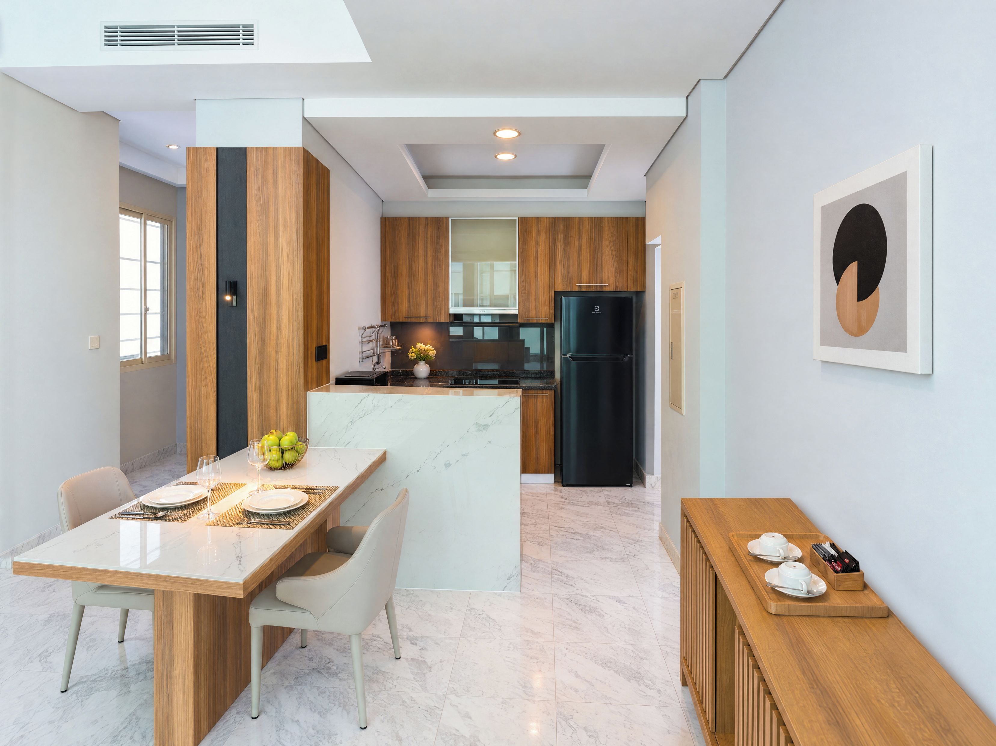 Una cocina moderna con una isla central, armarios de madera y un refrigerador negro.