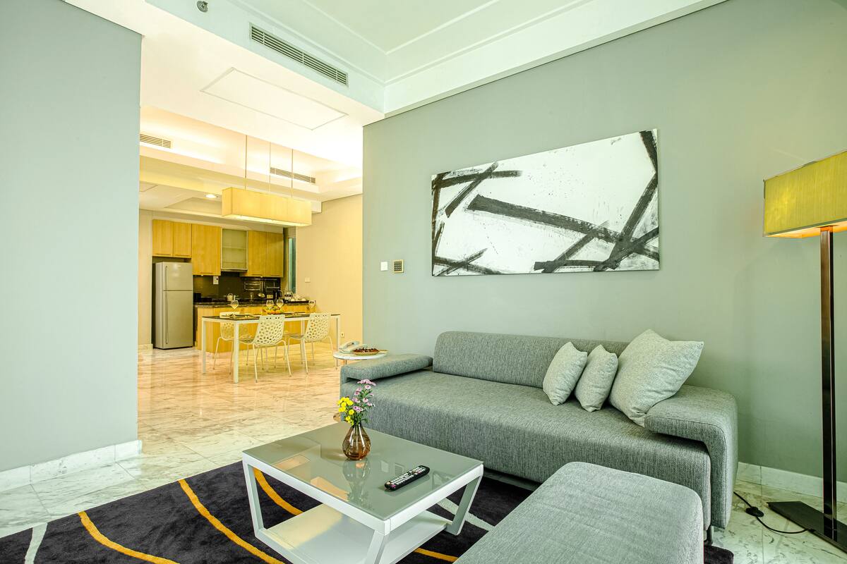 A modern living room with a grey sofa, a coffee table, and a painting on the wall.
