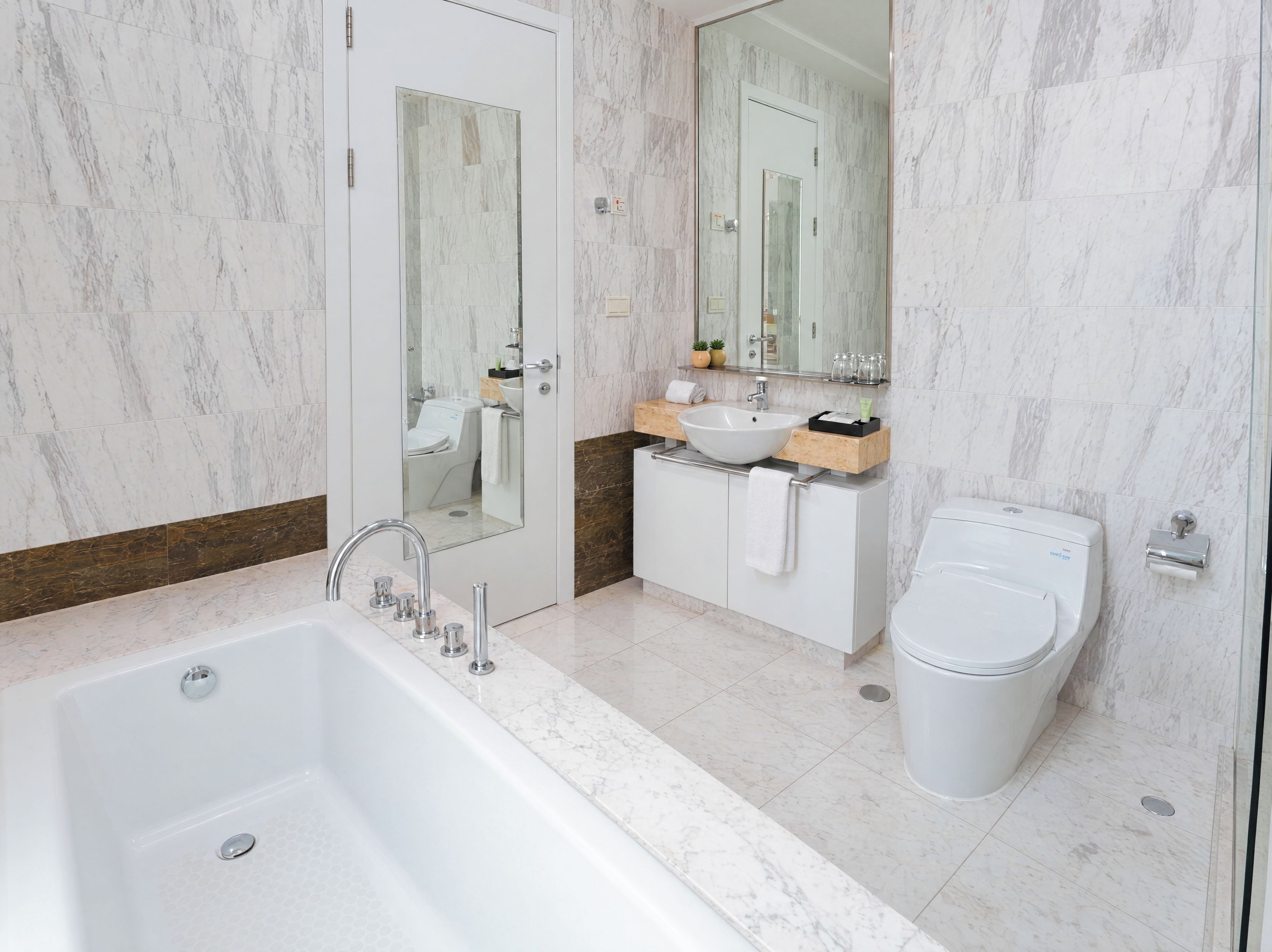 Un baño moderno con bañera, lavamanos, inodoro y espejo.