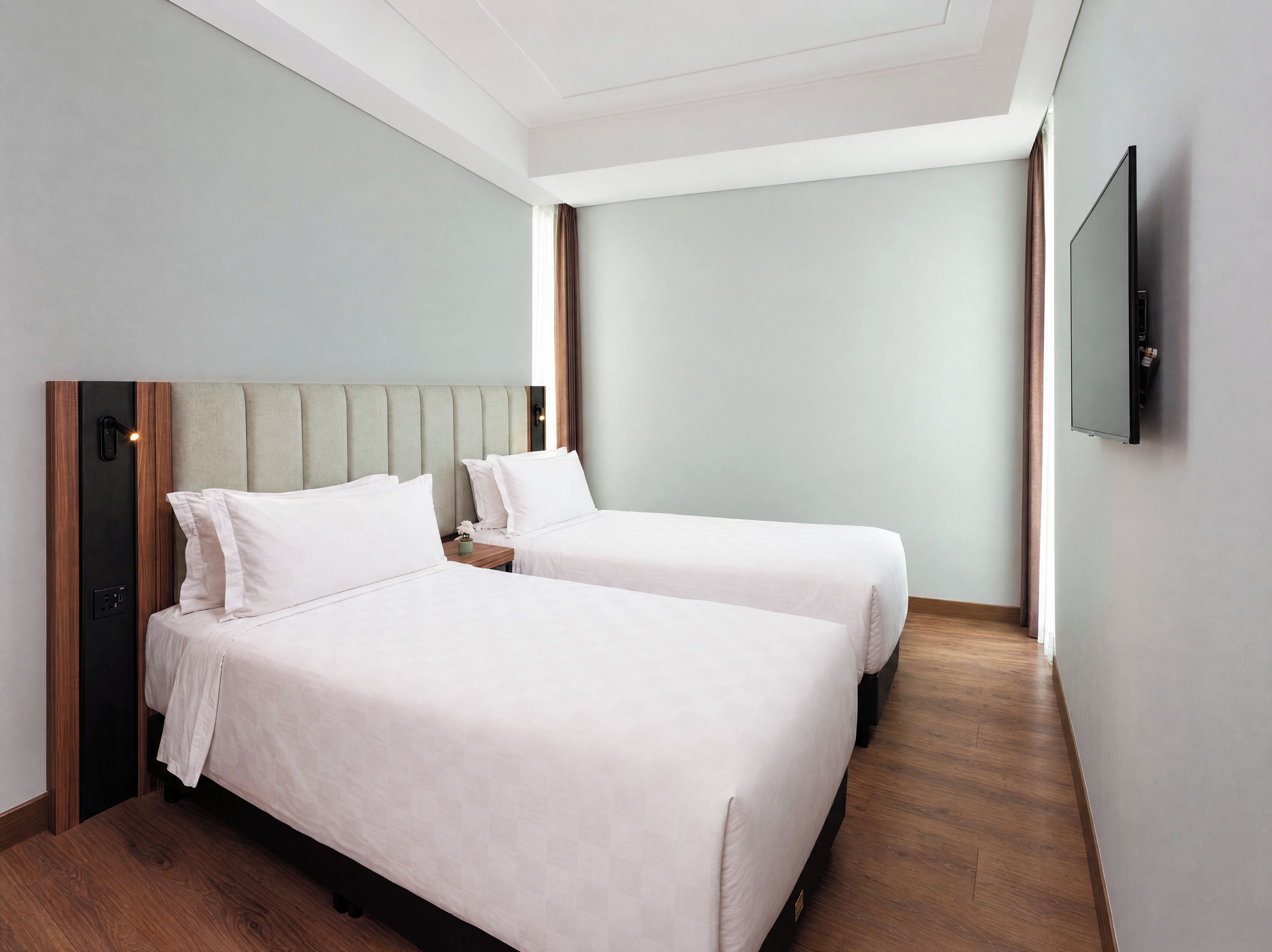 Une chambre d’hôtel avec deux lits, un téléviseur à écran plat et un plancher en bois.