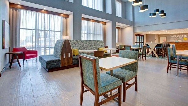 A spacious hotel lobby with high ceilings, large windows, and a mix of seating areas including sofas and chairs. - Hampton Inn & Suites Borger (Borger)