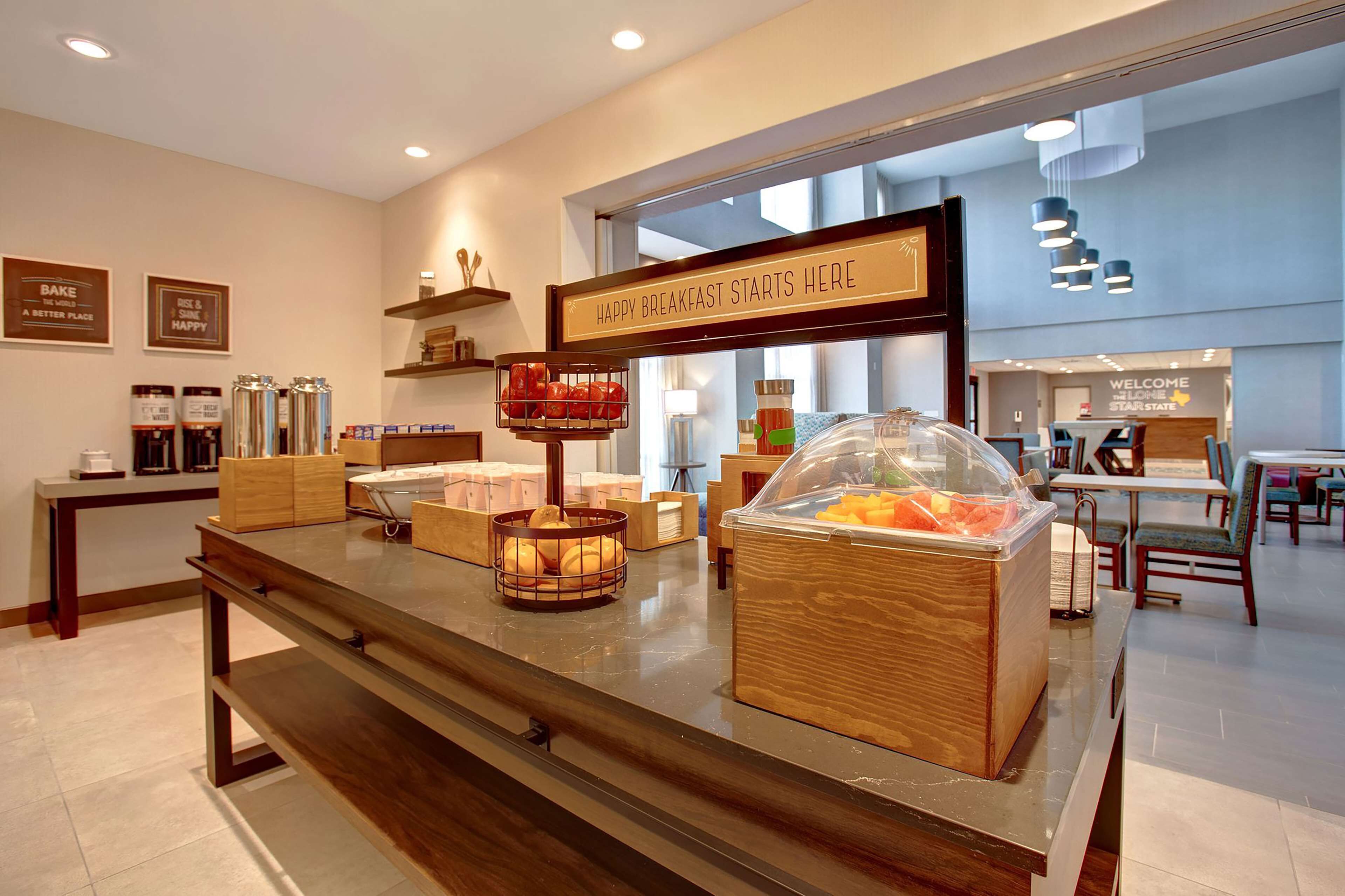 A breakfast buffet area with various food items and a sign that reads "HAPPY BREAKFAST STARTS HERE."