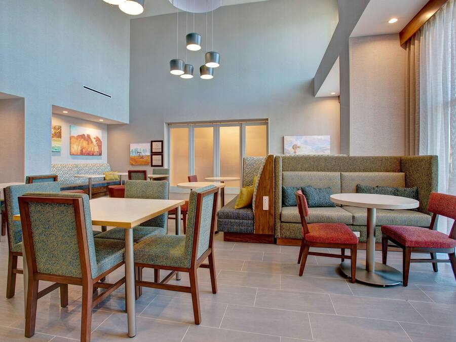 A modern hotel lobby with seating areas, tables, and artwork on the walls.