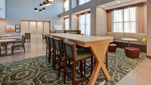 A spacious hotel lobby with a long wooden table, multiple chairs, a sofa, and a patterned carpet. - Hampton Inn & Suites Borger (Borger)