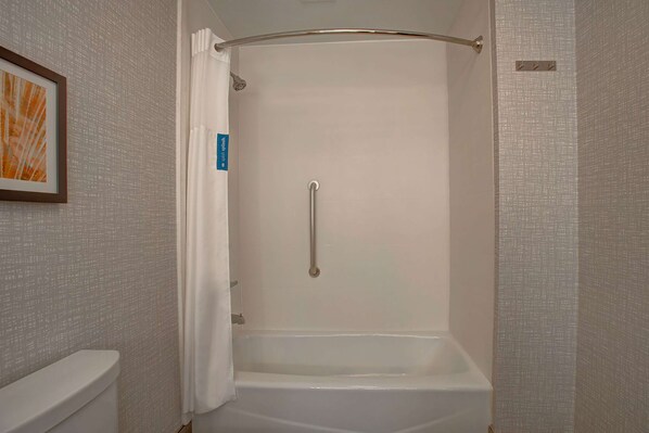 A shower area with a grab bar, a white bathtub, and a toilet.