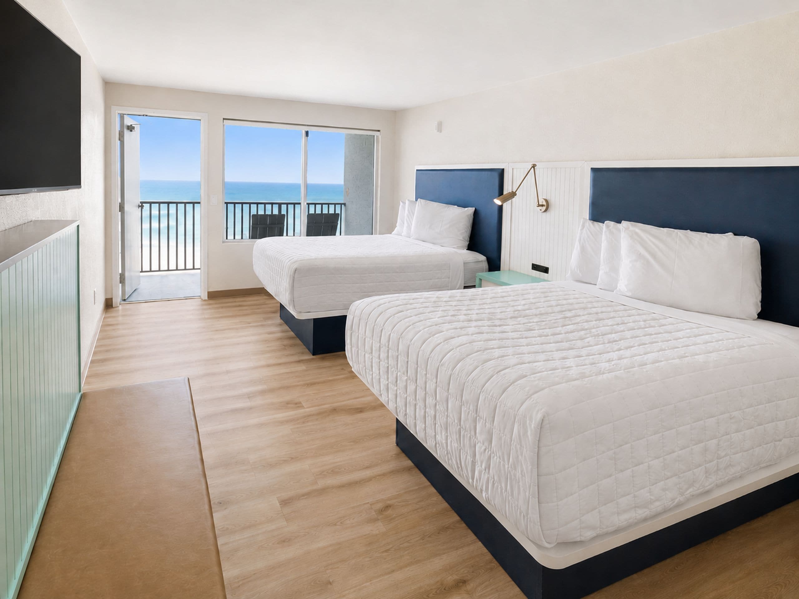 Une chambre d’hôtel avec deux lits, un balcon avec vue et une petite table.