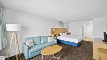 Una habitación de hotel con cama, sofá, una mesita y una lámpara.