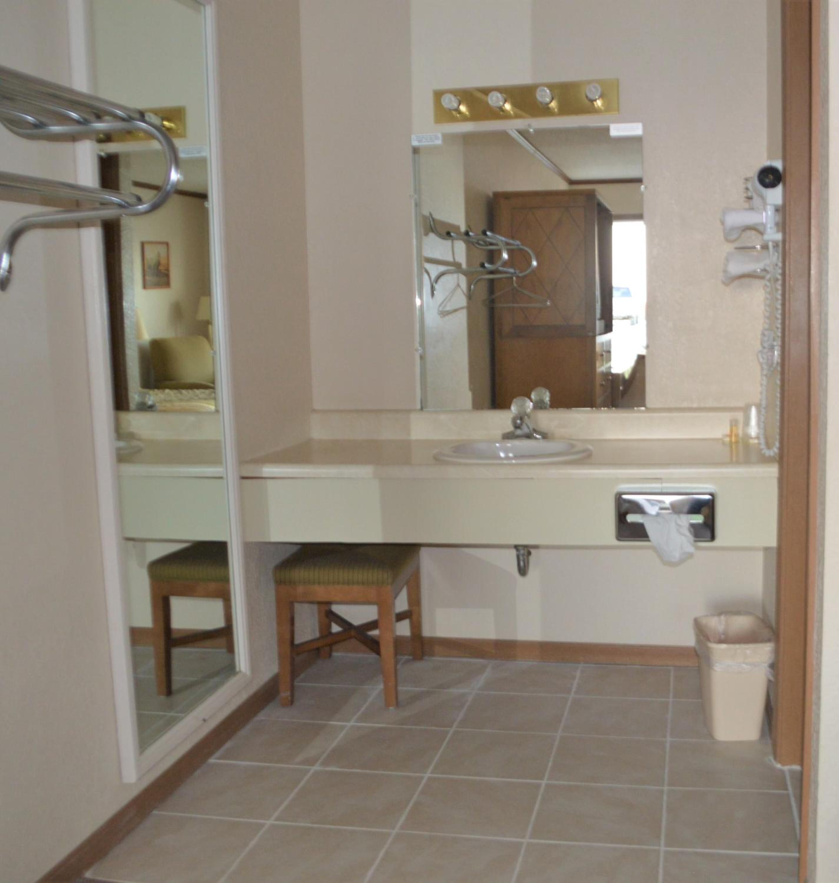 Une salle de bain équipée d’un lavabo, d’un miroir, d’un porte-serviettes et d’une chaise.