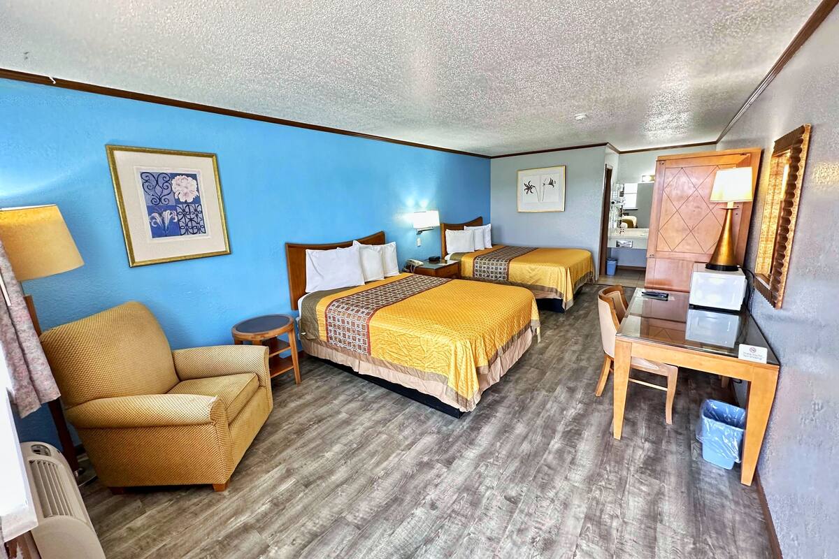 A hotel room with two beds, a sofa, a desk, and a chair.
