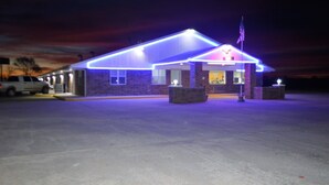 Un edificio de techos planos y fachada de ladrillo, con asta de bandera y una entrada bien iluminada.