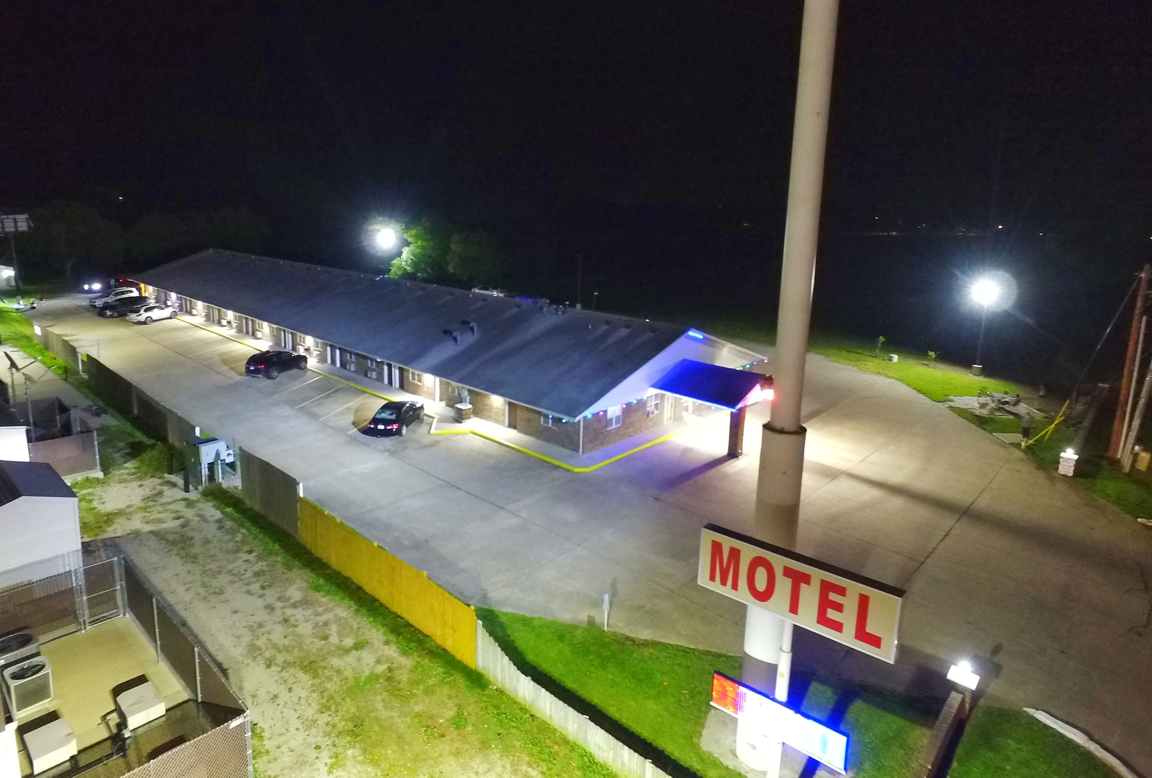 Un motel con un amplio estacionamiento, una gasolinera y un cartel que indica el nombre del motel.