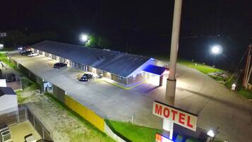 Un motel con un amplio estacionamiento, una gasolinera y un cartel que indica el nombre del motel.