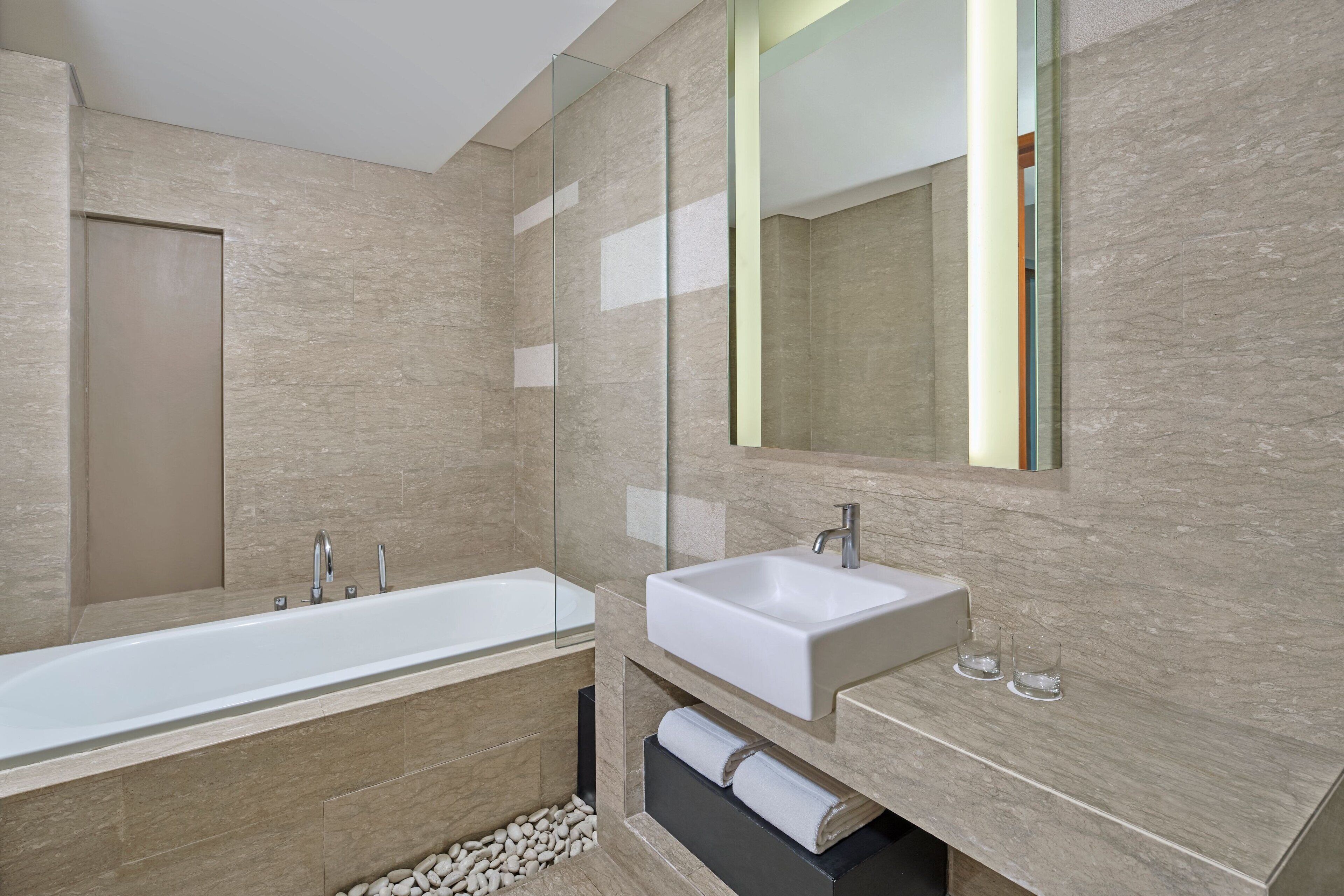 A modern bathroom with a large bathtub, a sink, and a mirror.