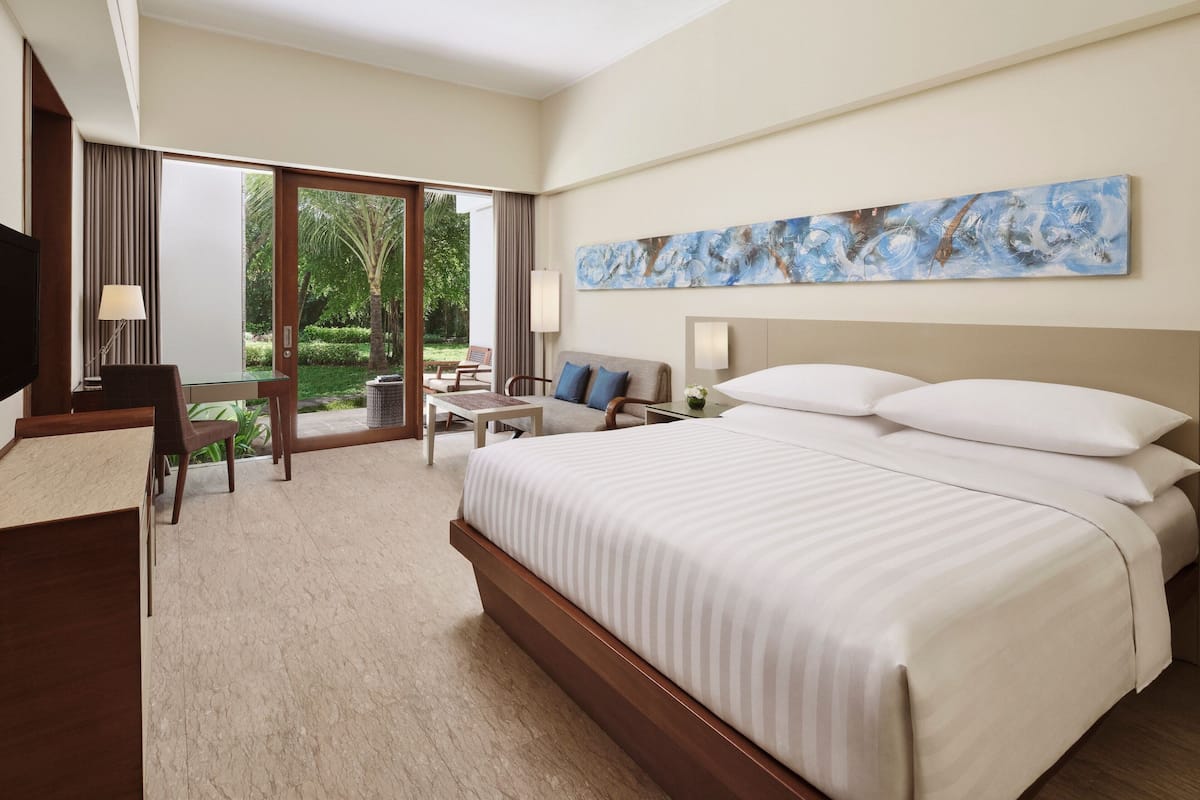 Quarto de hotel com uma cama grande, uma escrivaninha, uma cadeira e vista para o exterior.