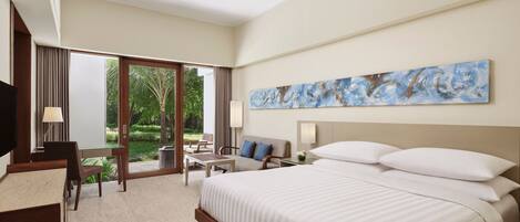 A hotel room with a large bed, a desk, a chair, and a view of the outdoors.