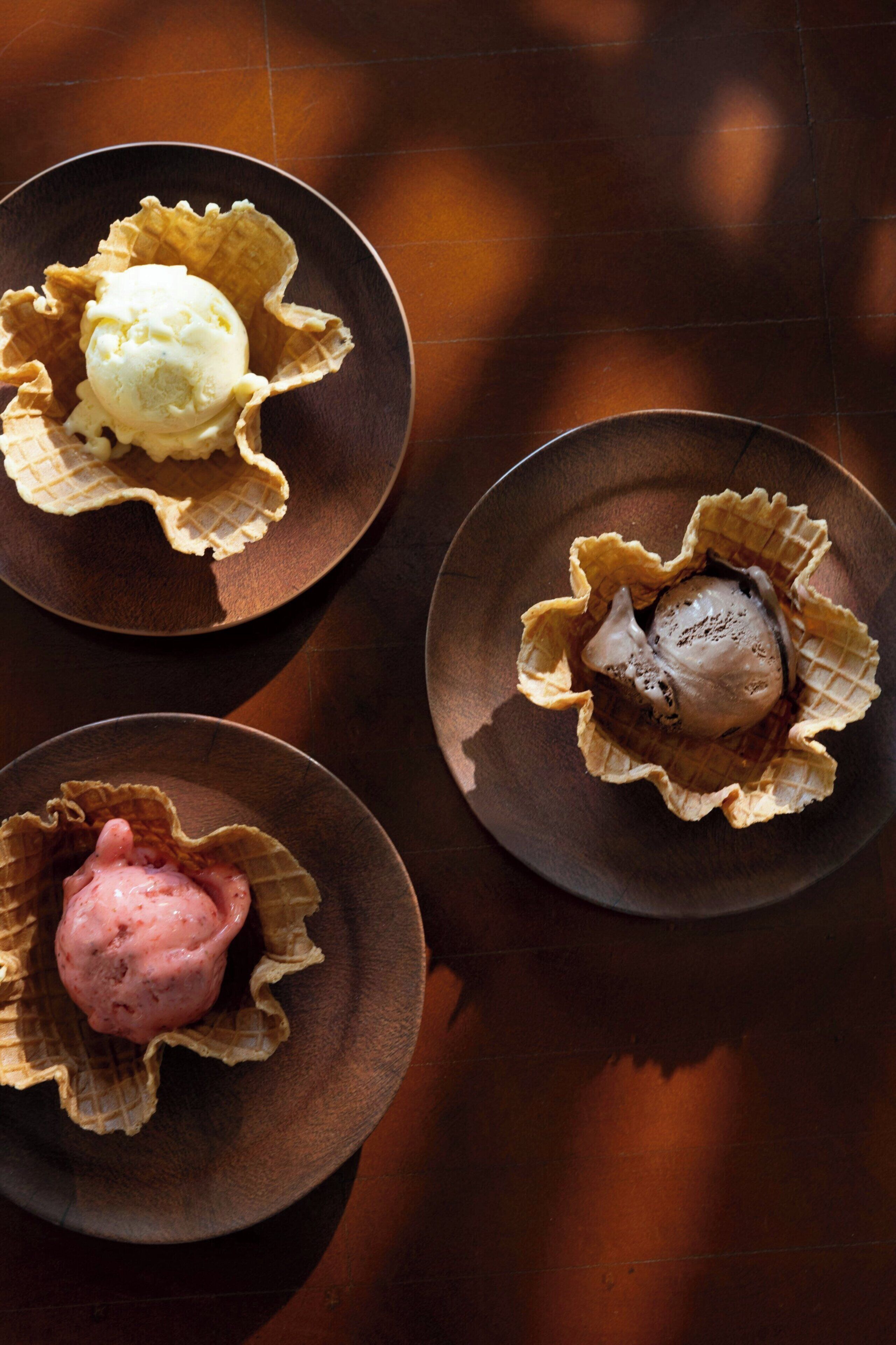 Three bowls of ice cream on a wooden table.