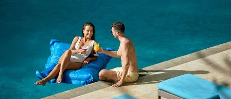 Un espace aménagé au bord de la piscine, avec des chaises longues et une personne assise sur un flotteur gonflable.