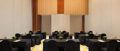 A conference room with multiple tables, black chairs, and a patterned carpet.