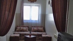 Un saló amb un sofà, dues taules laterals i una televisió.