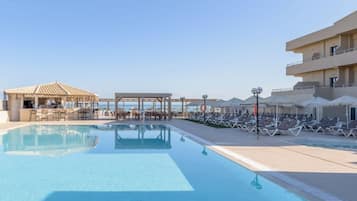 Alberca al aire libre, sombrillas en la alberca y camastros