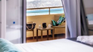 Ein Hotelzimmer mit Balkon, einem Bett, einem Sessel und einem Tisch mit einer Tasche und zwei Tassen.