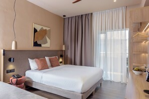 A modern hotel room with a large bed, a bedside table, a hanging coat rack, and a view of the outdoors through a large window. - Zeus Hotels Neptuno Beach - All Inclusive (Malevizi)