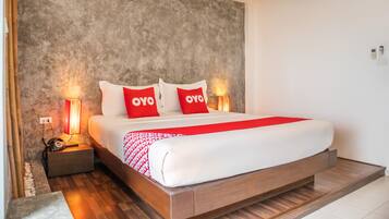 Una habitación de hotel moderna con una cama grande, dos mesitas de noche con lámparas, una pared con textura y una colcha roja y blanca.