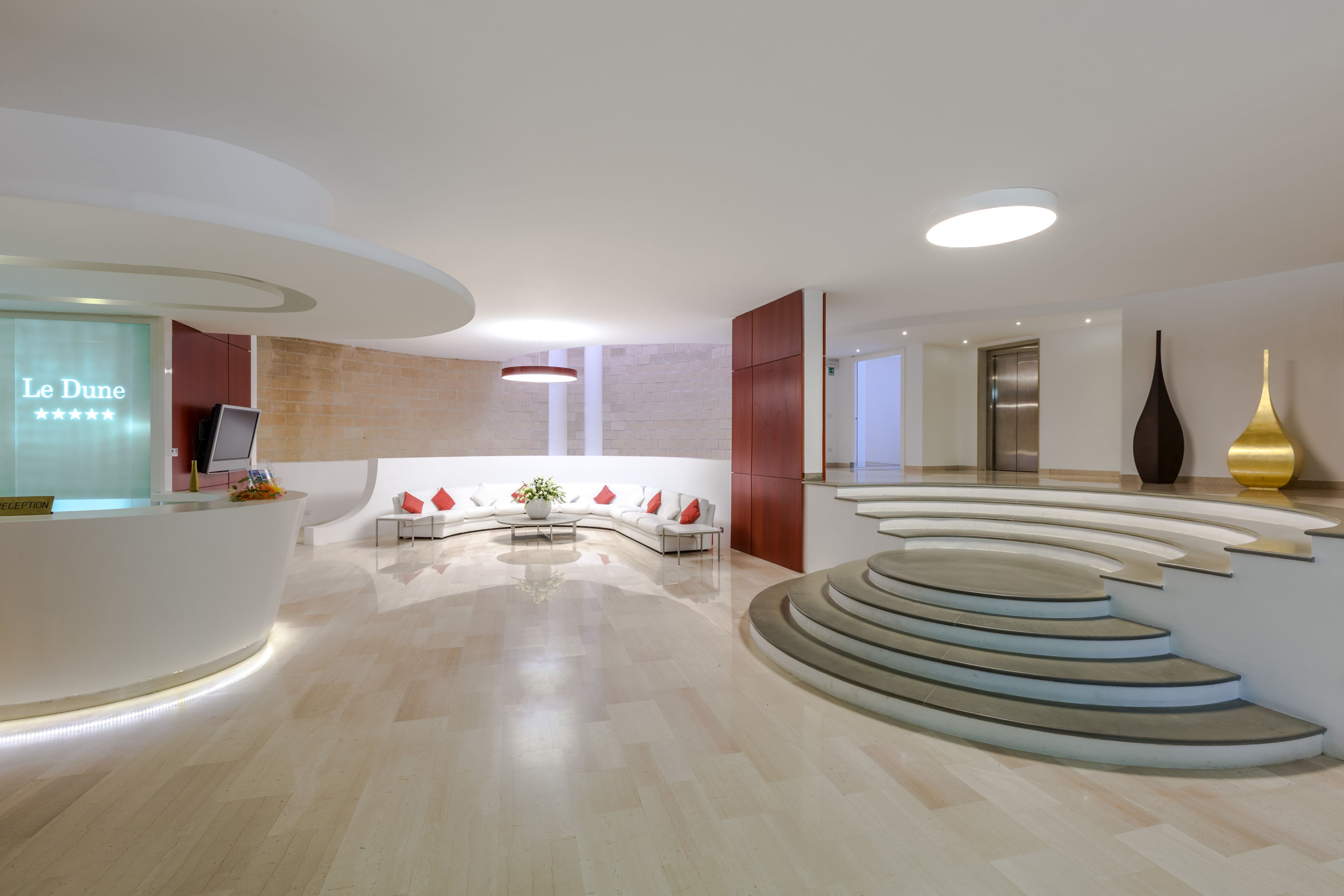 Un hall d’hôtel moderne avec un comptoir d’accueil, un espace salon et un escalier.