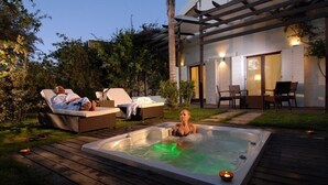 A hot tub in a backyard with lounge chairs and a patio area.