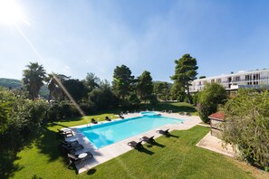 A swimming pool with lounge chairs, surrounded by a well-maintained lawn and trees. - Gusmay Resort – Hotel Gusmay & Suite Le Dune (Peschici)