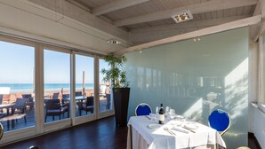 A dining area with a view of the beach, large windows, and a table set for two.