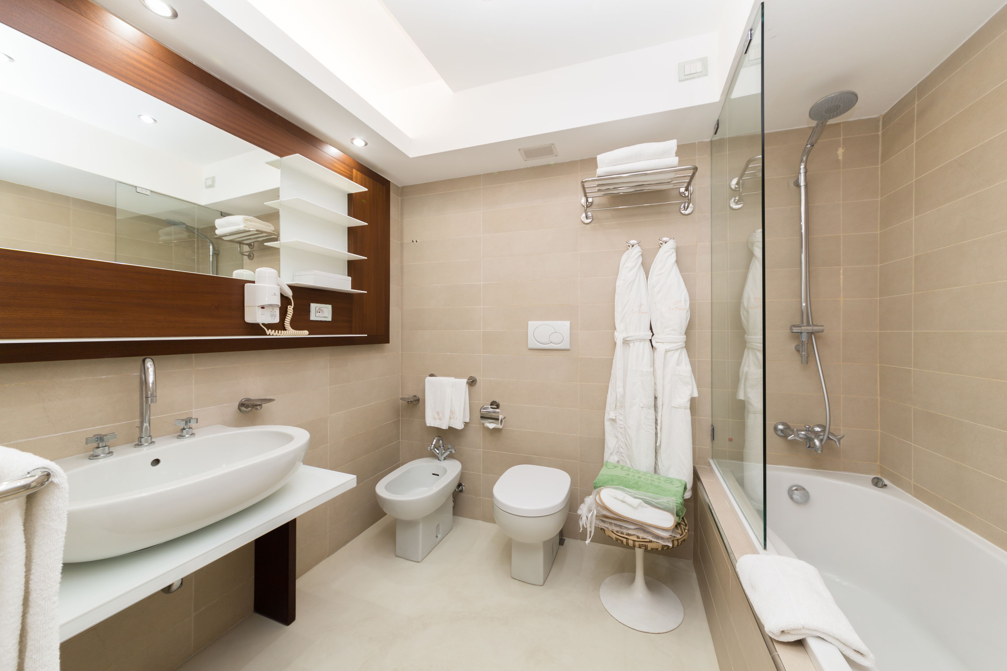 A modern bathroom with a large sink, bidet, toilet, and bathtub.