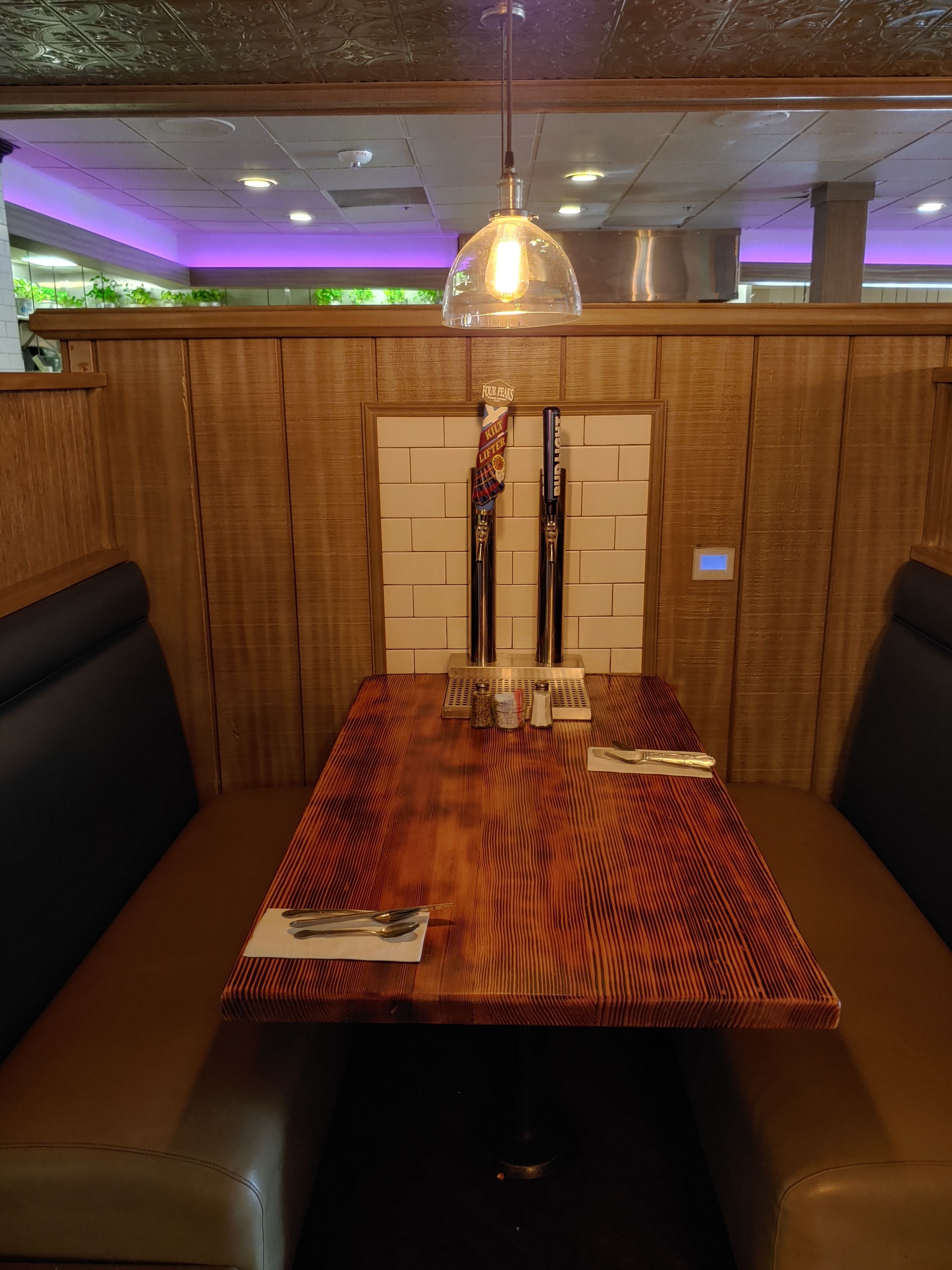 A restaurant booth with a wooden table and black leather seats.