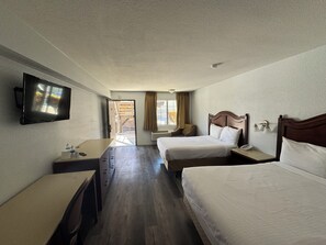 Habitación de hotel con dos camas, televisión, escritorio y ventana con cortinas.