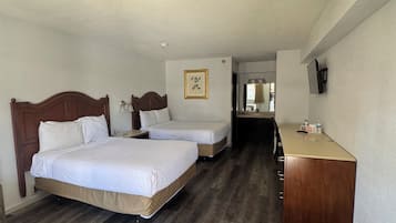 Ein Hotelzimmer mit zwei Betten, einem Holzschrank, einem Schreibtisch und einem gerahmten Bild an der Wand.