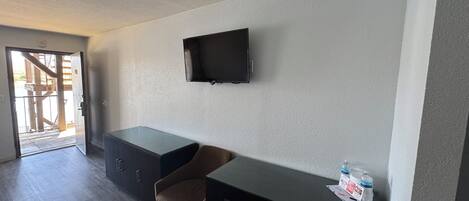Una habitación pequeña y moderna con escritorio, silla y televisor de pantalla plana montado en la pared.