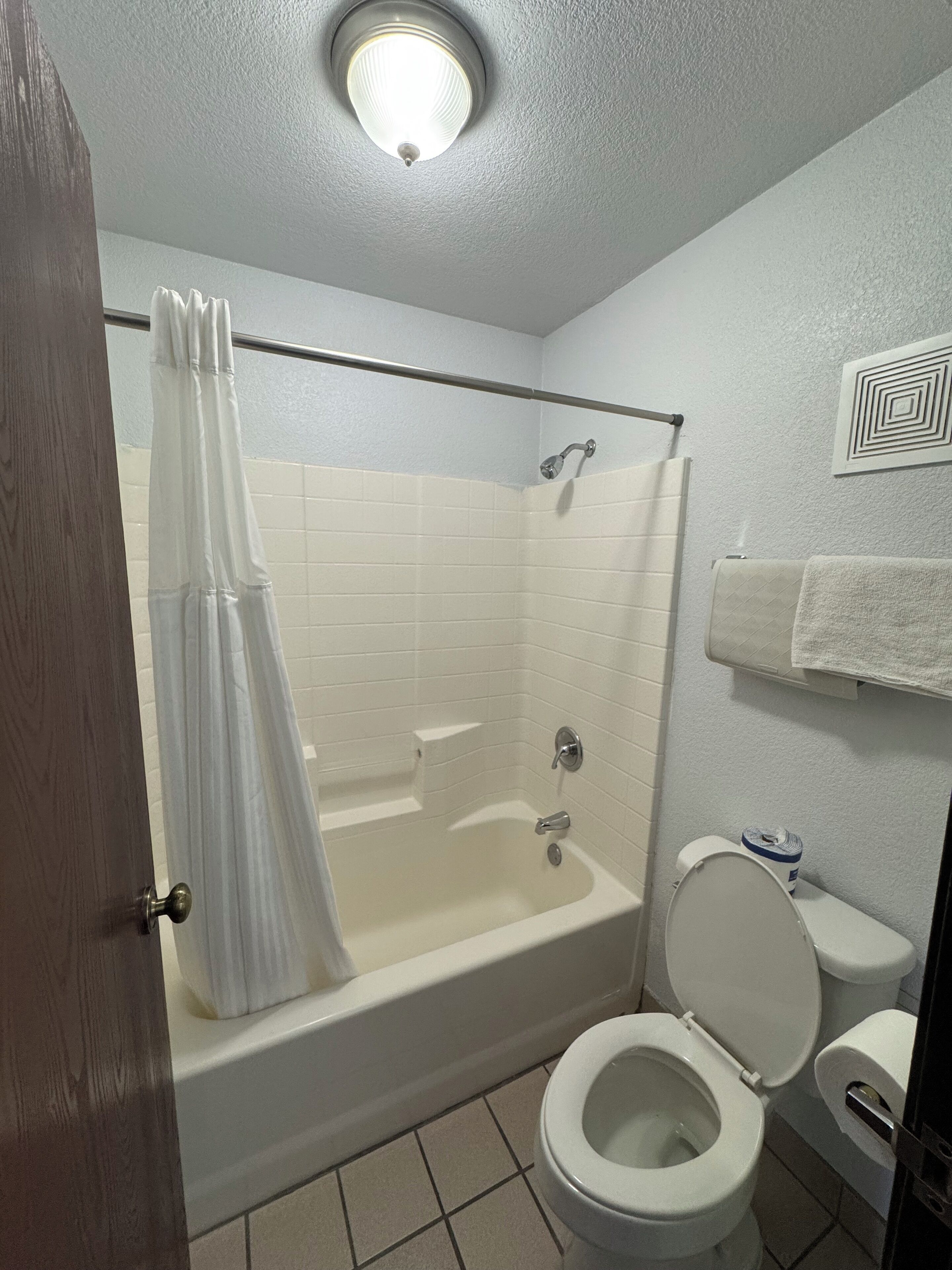 Un baño con bañera, inodoro y cortina de ducha.