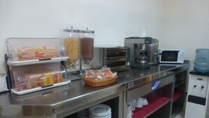 Montaje de bufé con dispensadores de comida, una máquina de café y un microondas.