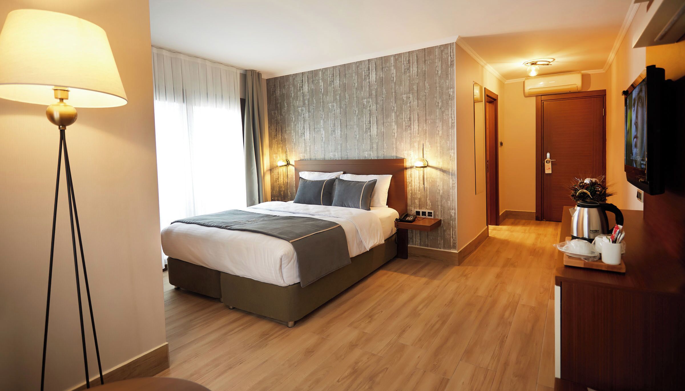 Una habitación de hotel con cama, mesita de noche, lámpara y televisor.